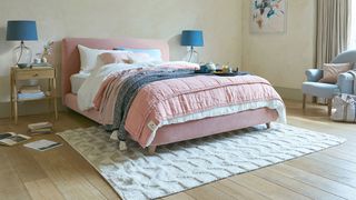 small bedroom with pink bed and cream rug
