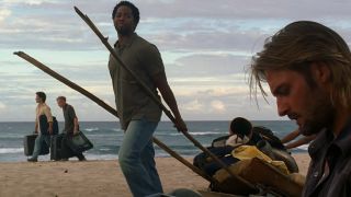 Harrold Perrineau as Michael walking on a beach past Sawyer in Lost