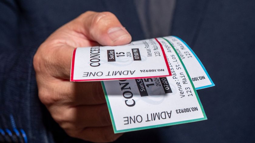 A hand holding concert tickets