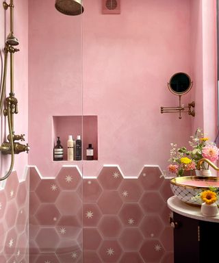 pink shower area with half pink tiles and half painted, alcoves for accessories, brass shower,