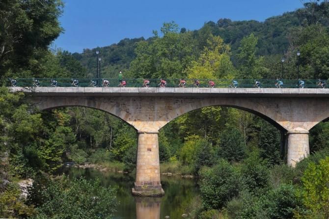 The peloton makes its way over a river