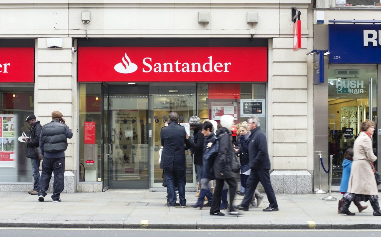 People queuing up or walking past a branch of Santander bank on a high street