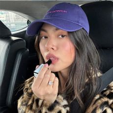 A woman applying lipstick while sitting in a car