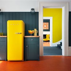 kitchen area with red floor and yellow fridge