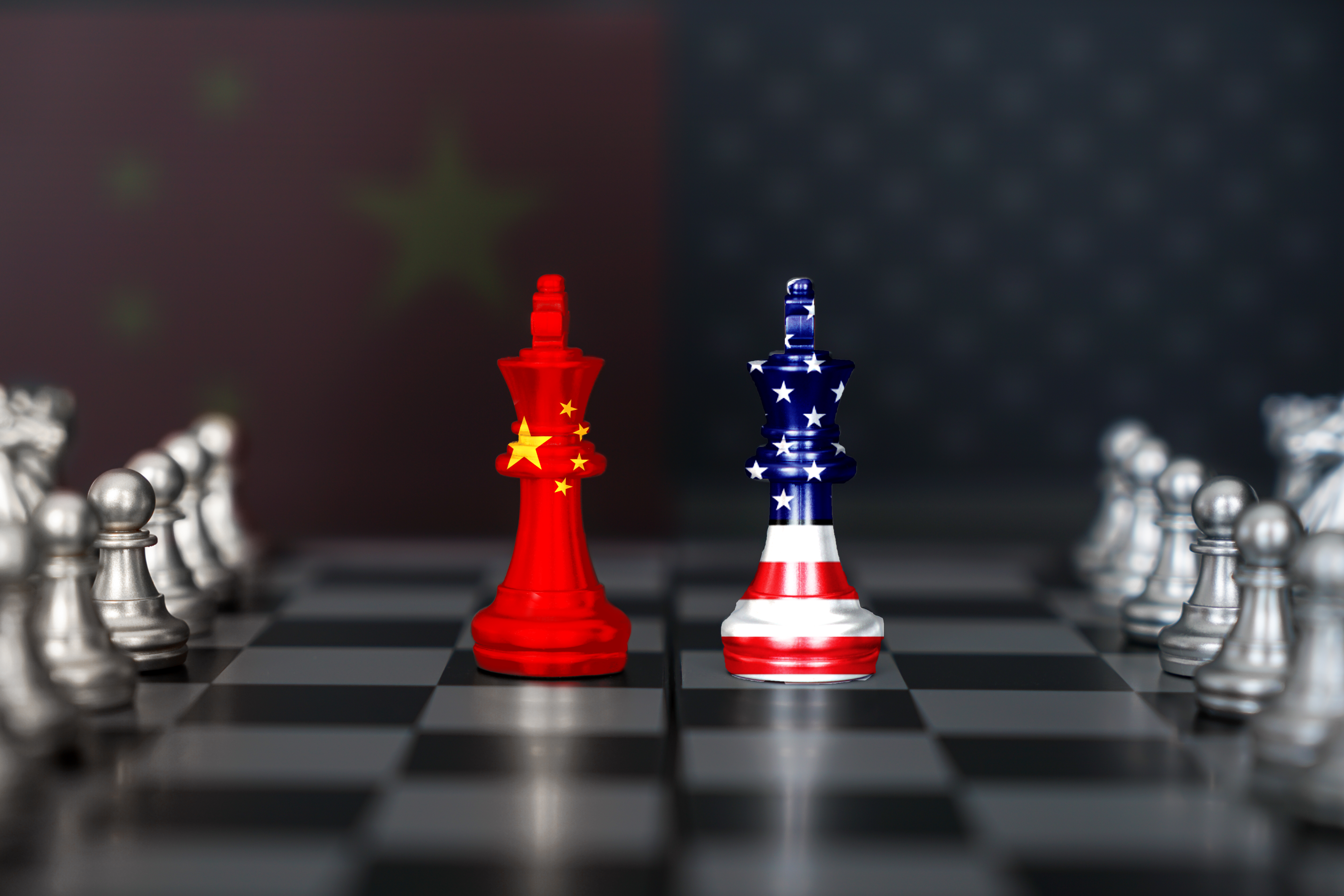 China and US flags on chess pieces in the middle of a chess board.