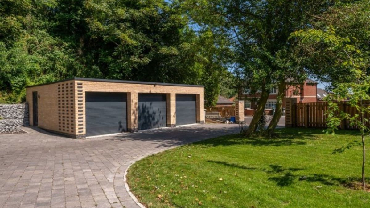 At the end of the drive is three brick built garages with black shutters