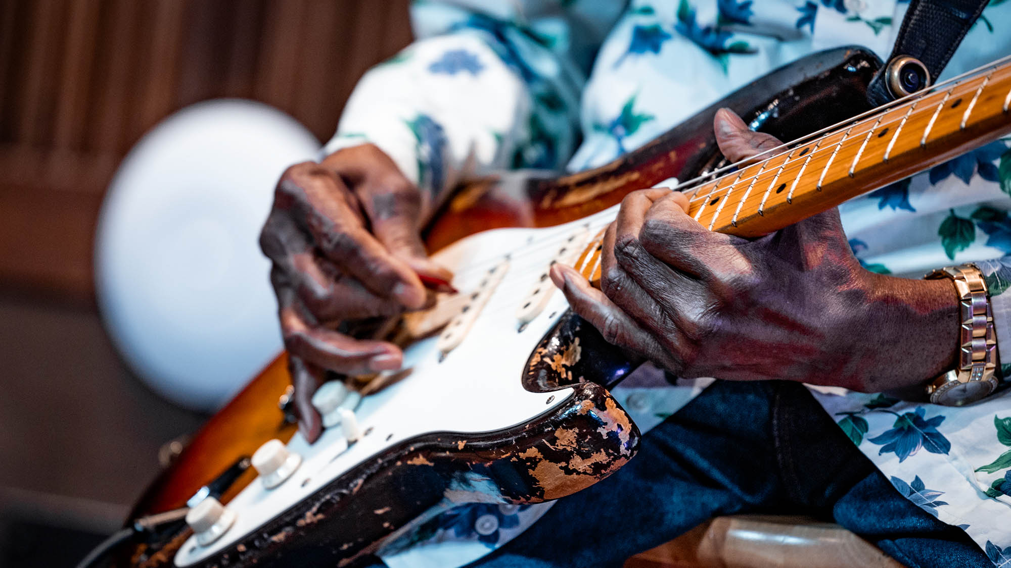 A photo showing Buddy Guy's hands as he plays a sunburst Fender Stratocaster