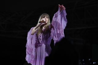Taylor Swift wearing a purple alberta ferretti dress with long ruffled sleeves while performing at the eras tour