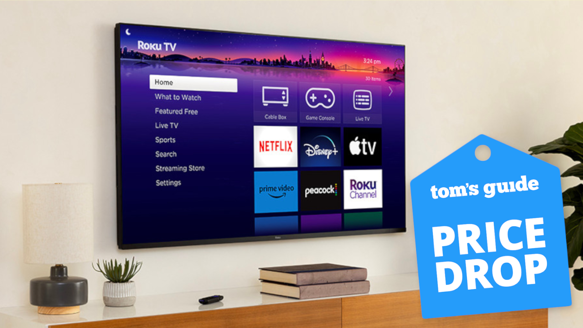 A wall-mounted Roku Pro Series TV displaying the Roku OS home screen. On the right-hand side of the image is a blue-colored badge that reads: Tom's Guide - Price Drop