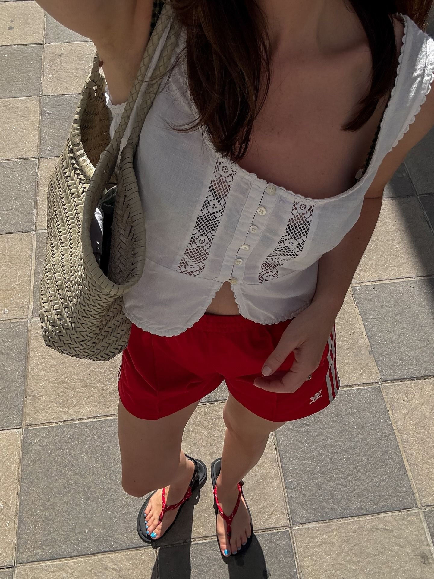 Woman in white embroidered top and red track shorts
