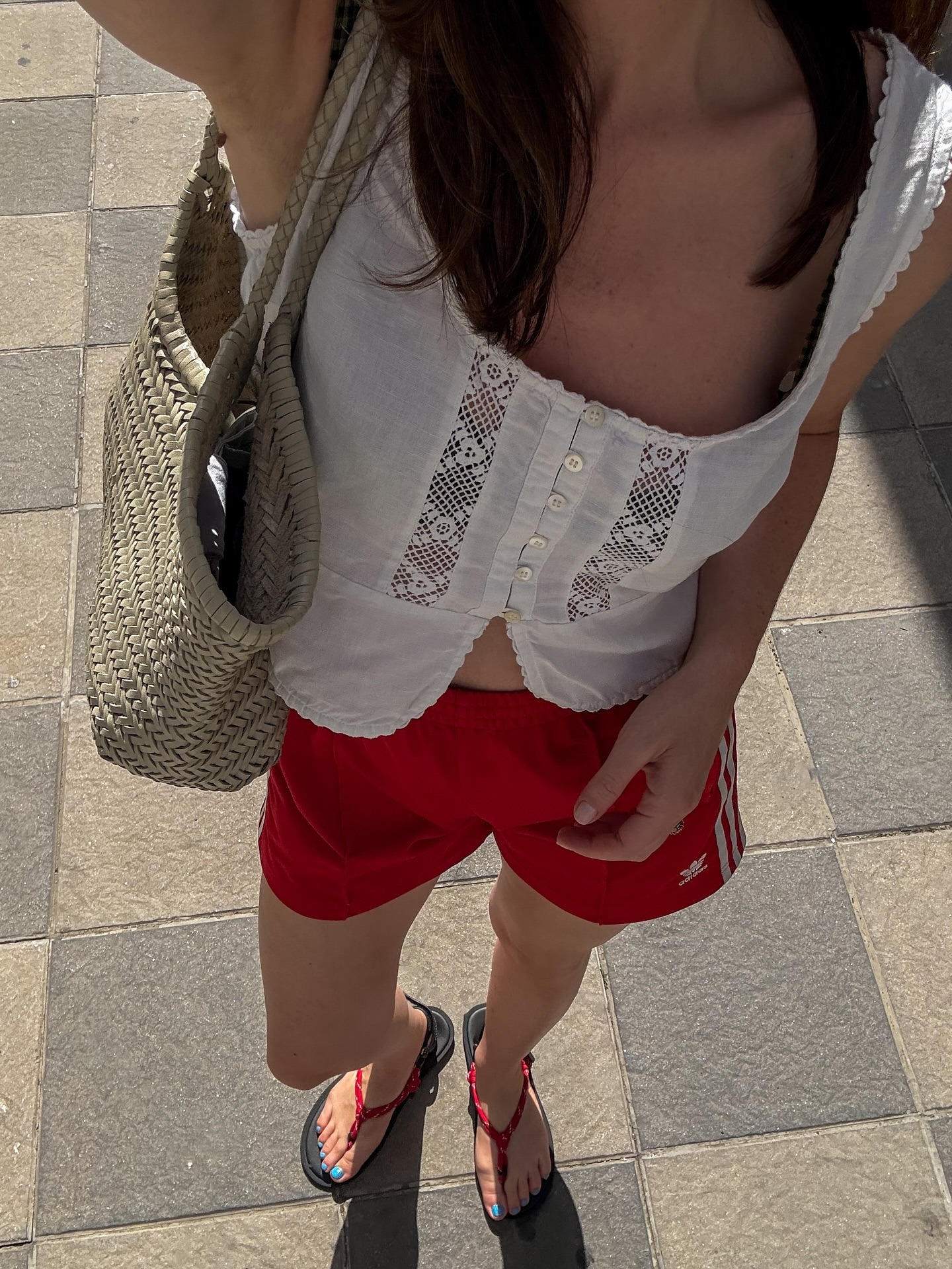 Woman in white embroidered top and red track shorts
