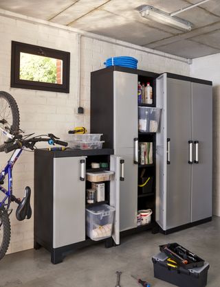 Corner of garage with bike, tool box and cupboards filled with boxes and other items