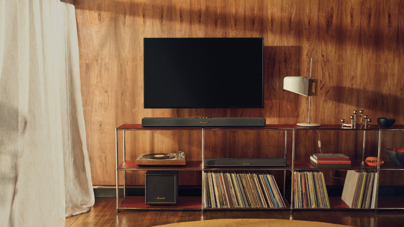 two marshall soundbars and a subwoofer sit at the bottom of a TV on a shelf