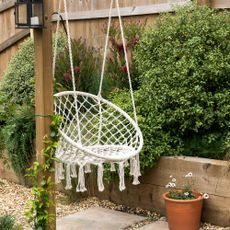 Hanging chair attached to a wooden garden pergola 