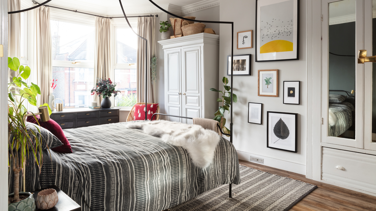 Neutral bedroom with lots of wall art. There is a metal framed bed with dark duvet se and a fur blanket