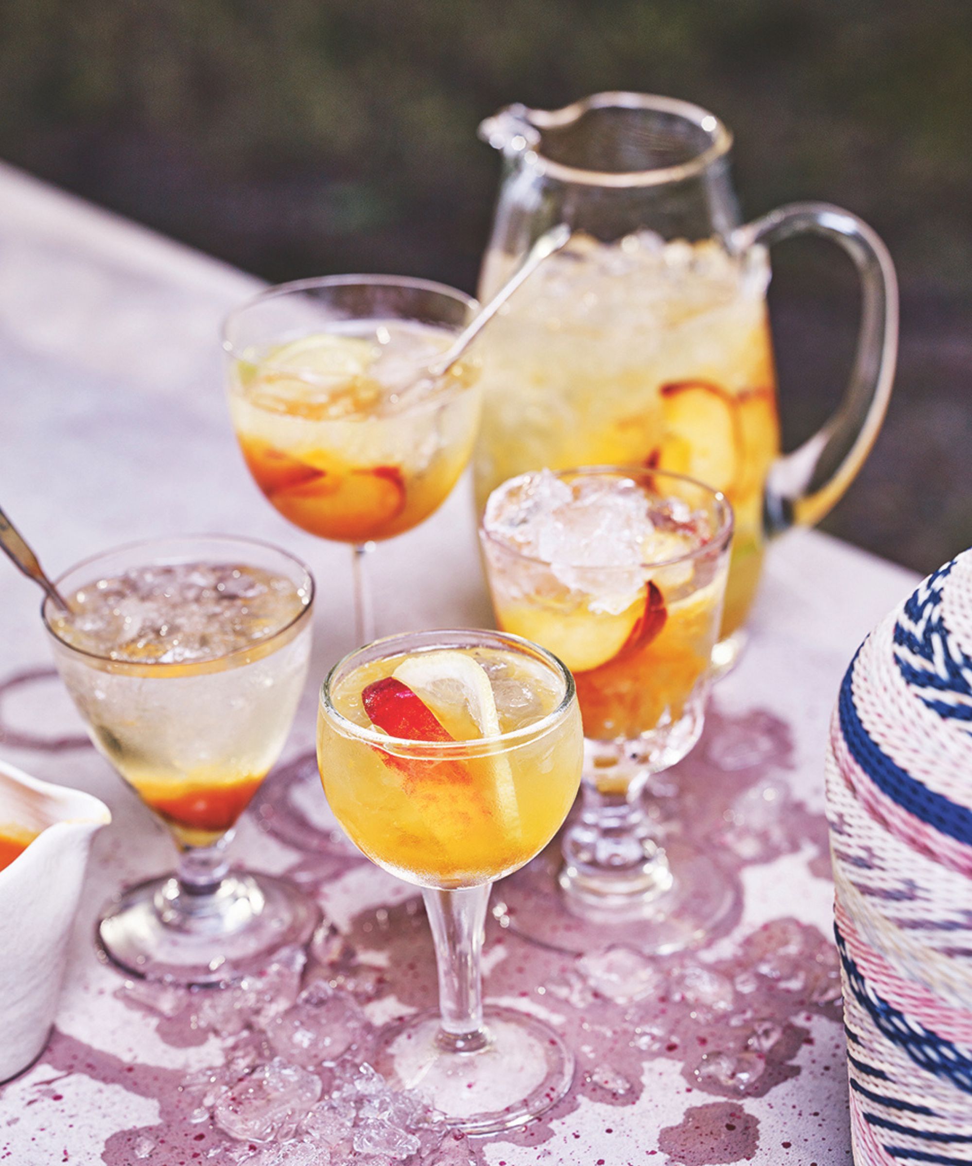 A jug and glasses of sangria with fruit and ice in