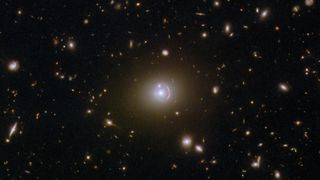 A ring of light with a bright galaxy at its center and another galaxy aligned with the ring like an engagement ring
