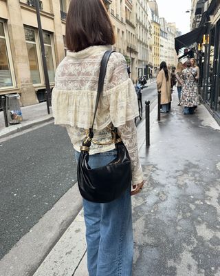 @smythsisters wearing a ruffled lace blouse and jeans