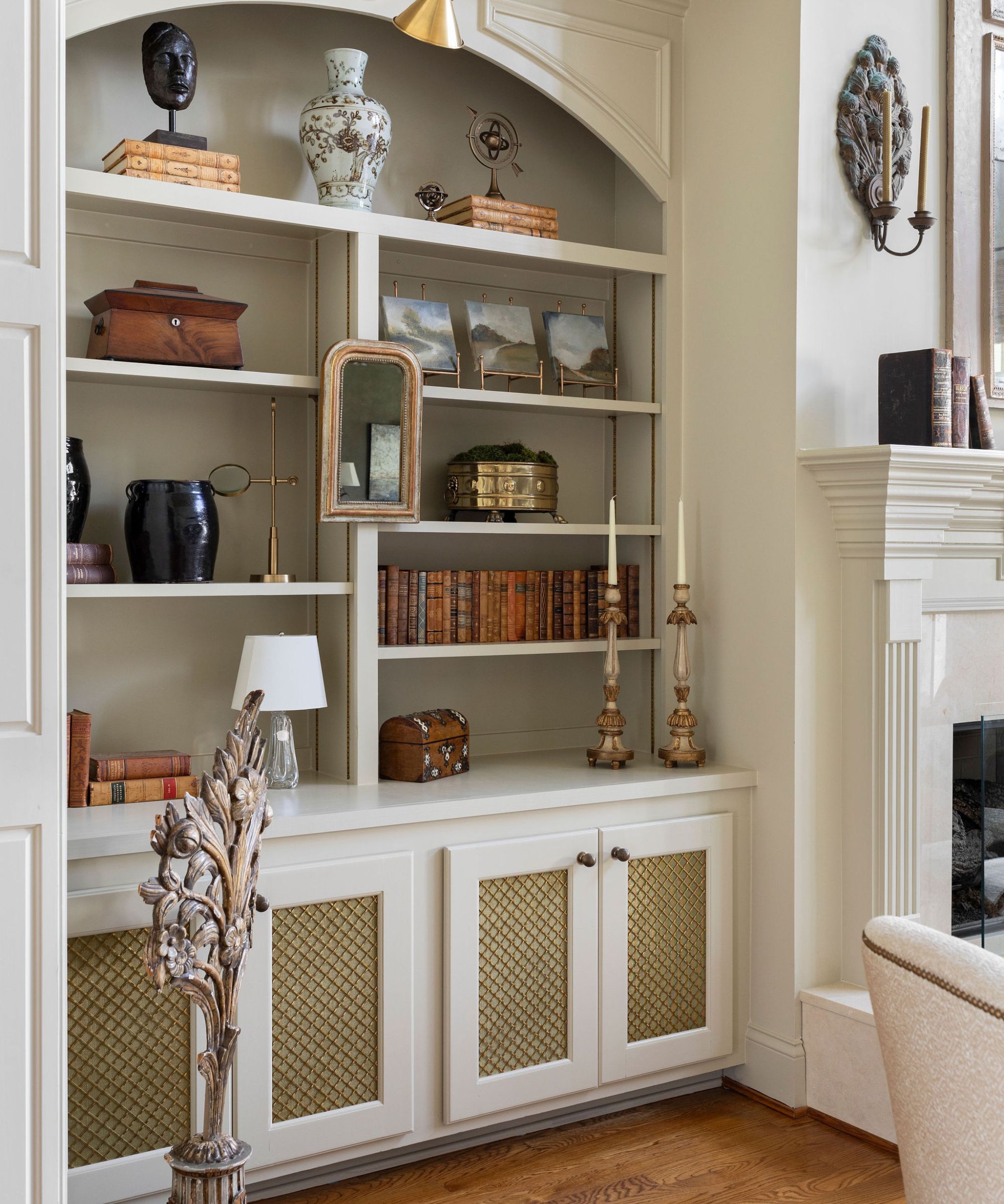 Cream painted bookshelves with antique books, trinkets and paintings