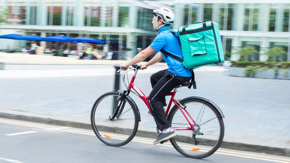 Courier On Bicycle Delivering Food In City 