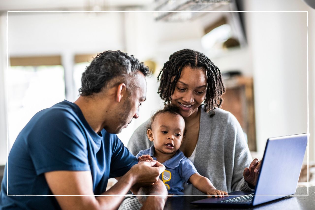 mother, father and baby sitting together at home looking at a laptop together