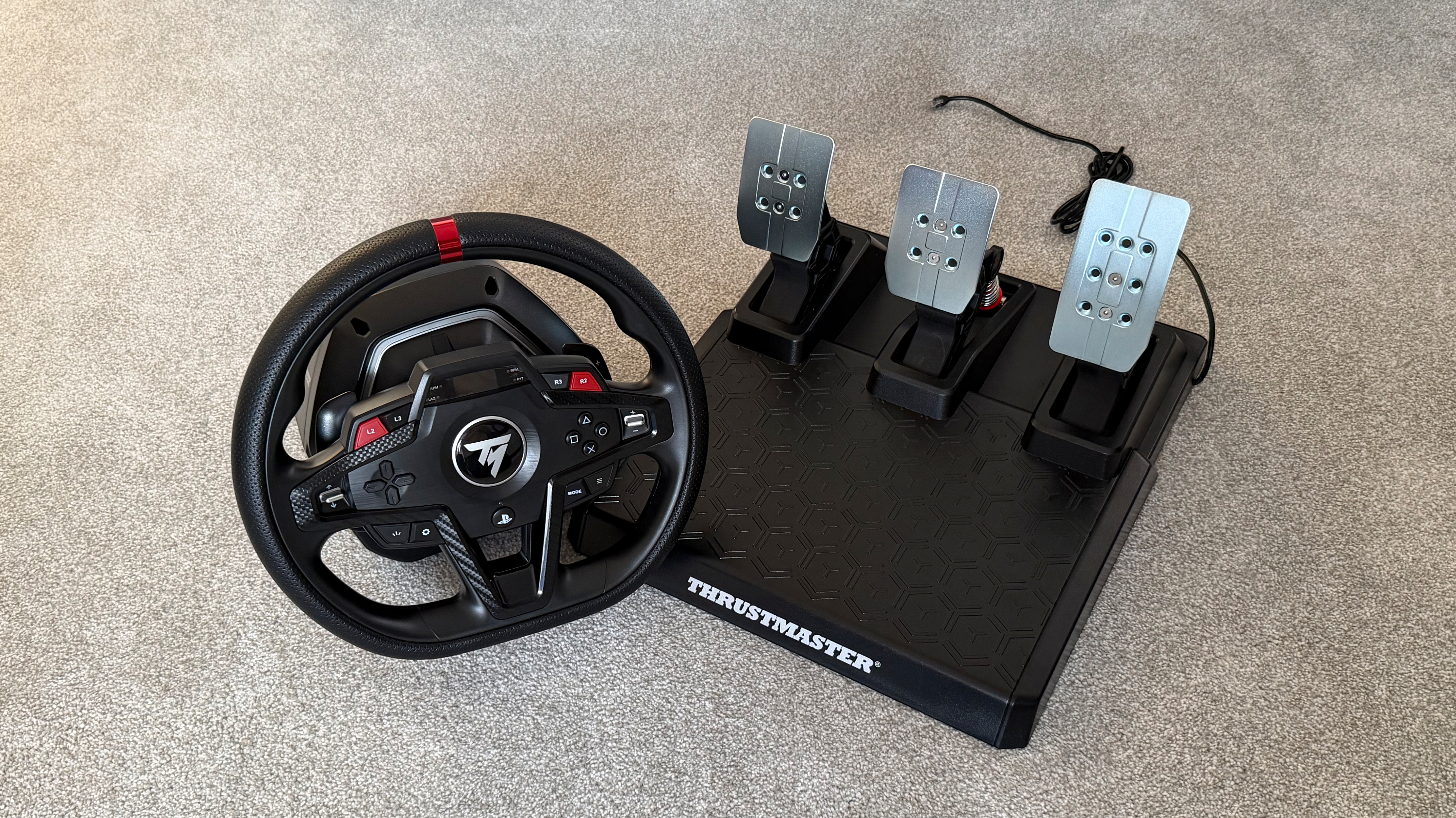 A Thrustmaster T248R and its pedals on a grey carpet