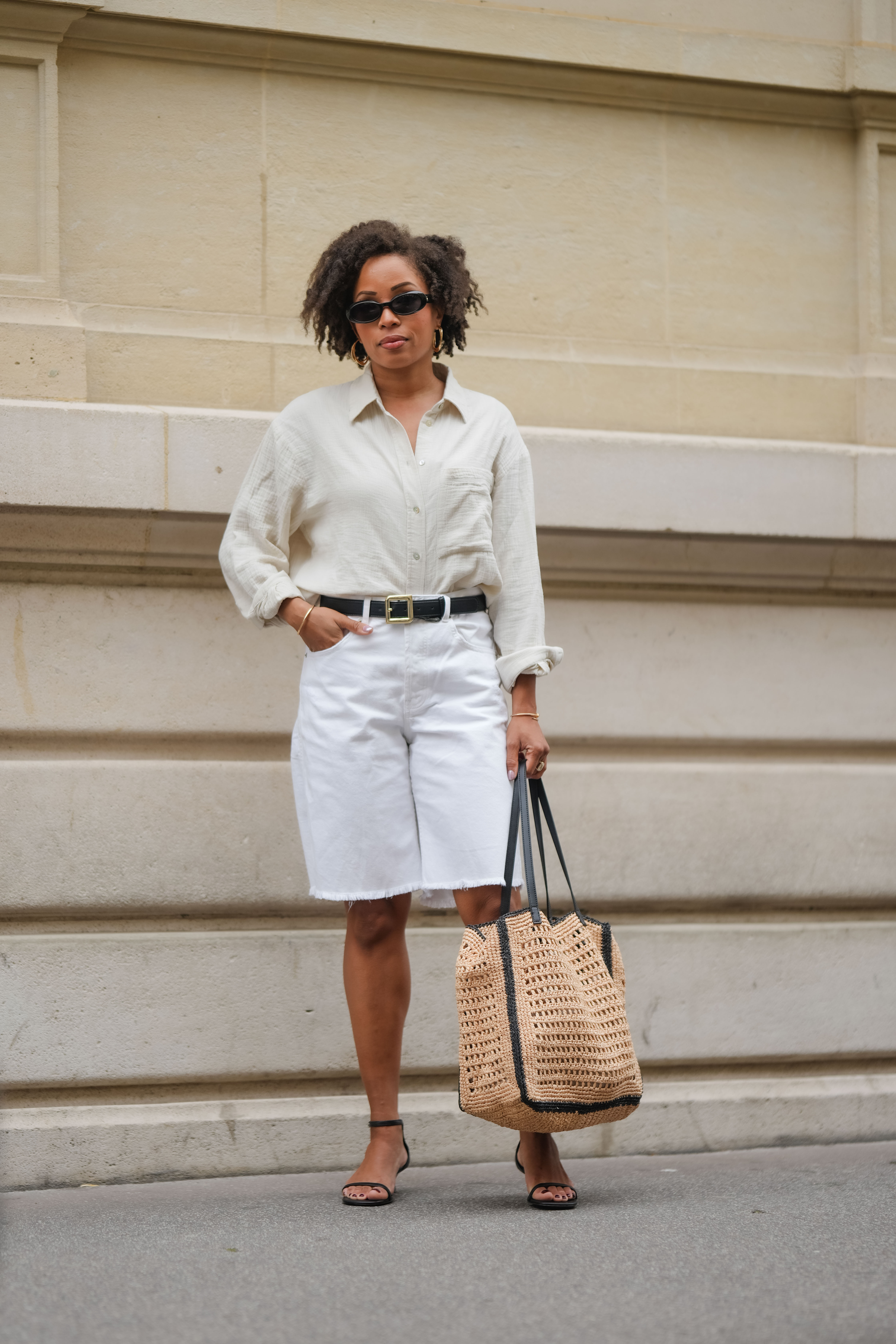 woman wearing button-down shirt, bermuda shorts, sandals, and woven bag