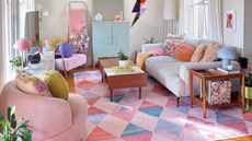 A pink living area with a couch, coffee table, rug, and cabinet