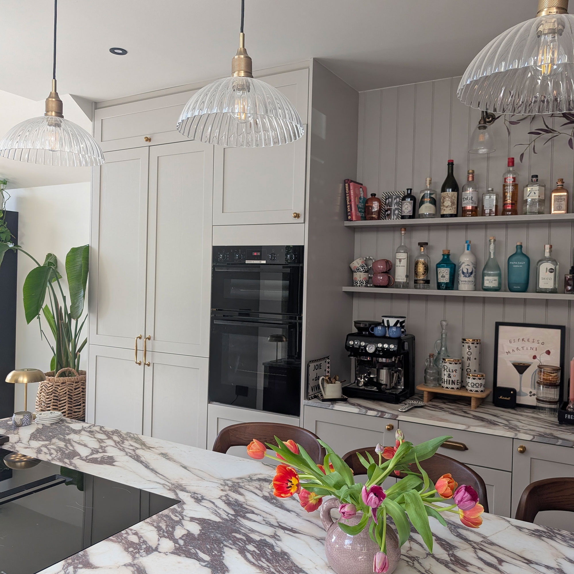 Marble topped kitchen island with three ribbed glass pendant lights above