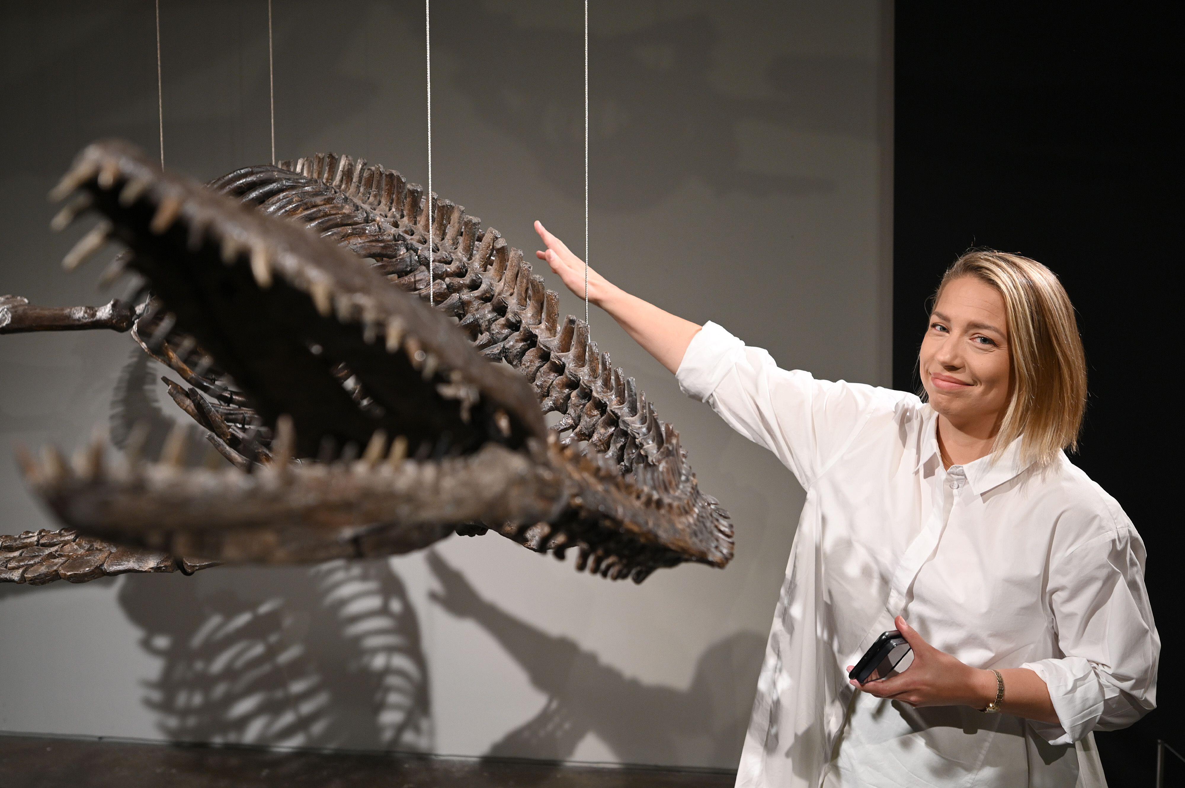 Cassandra Hatton posing next to a Plesiosaur fossil in 2023.