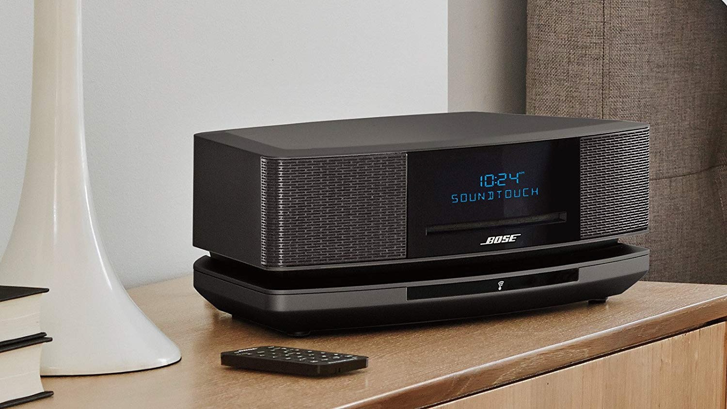 Bose Wave SoundTouch Music System IV in black on a table next to a bed