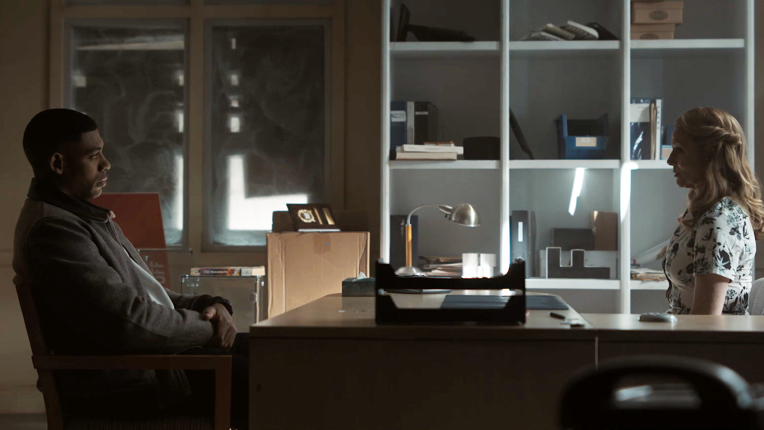 John Stewart and Lianna sitting across a table in Lanterns episode 3