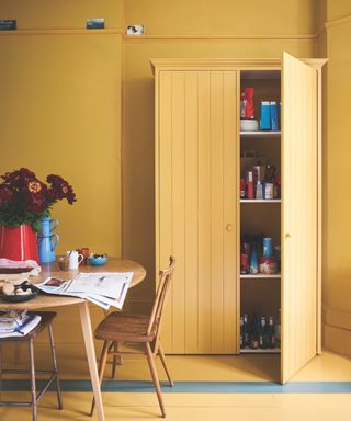 Yellow kitchen color drenched, yellow floors, walls and pantry, dining table and chairs