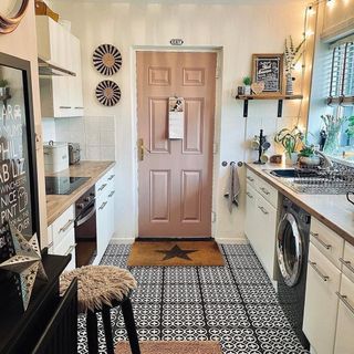 Kitchen with a pink door and black and white flooring
