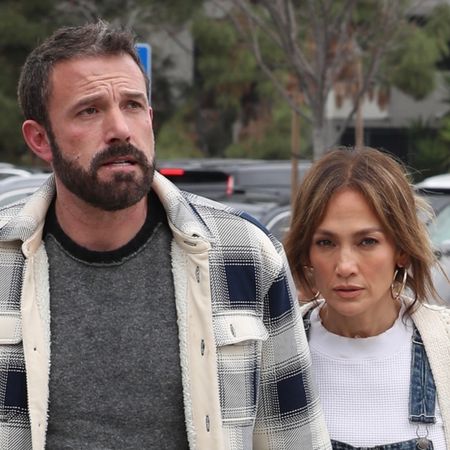 Jennifer Lopez and Ben Affleck walking hand in hand, Lopez wearing denim overalls with a cardigan and UGG platforms.