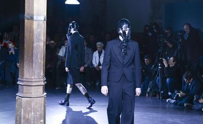 Men with long black hair in their faces walking the runway