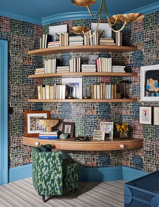 A bedroom with patterned wallpaper and bookshelves winding around a curved wall