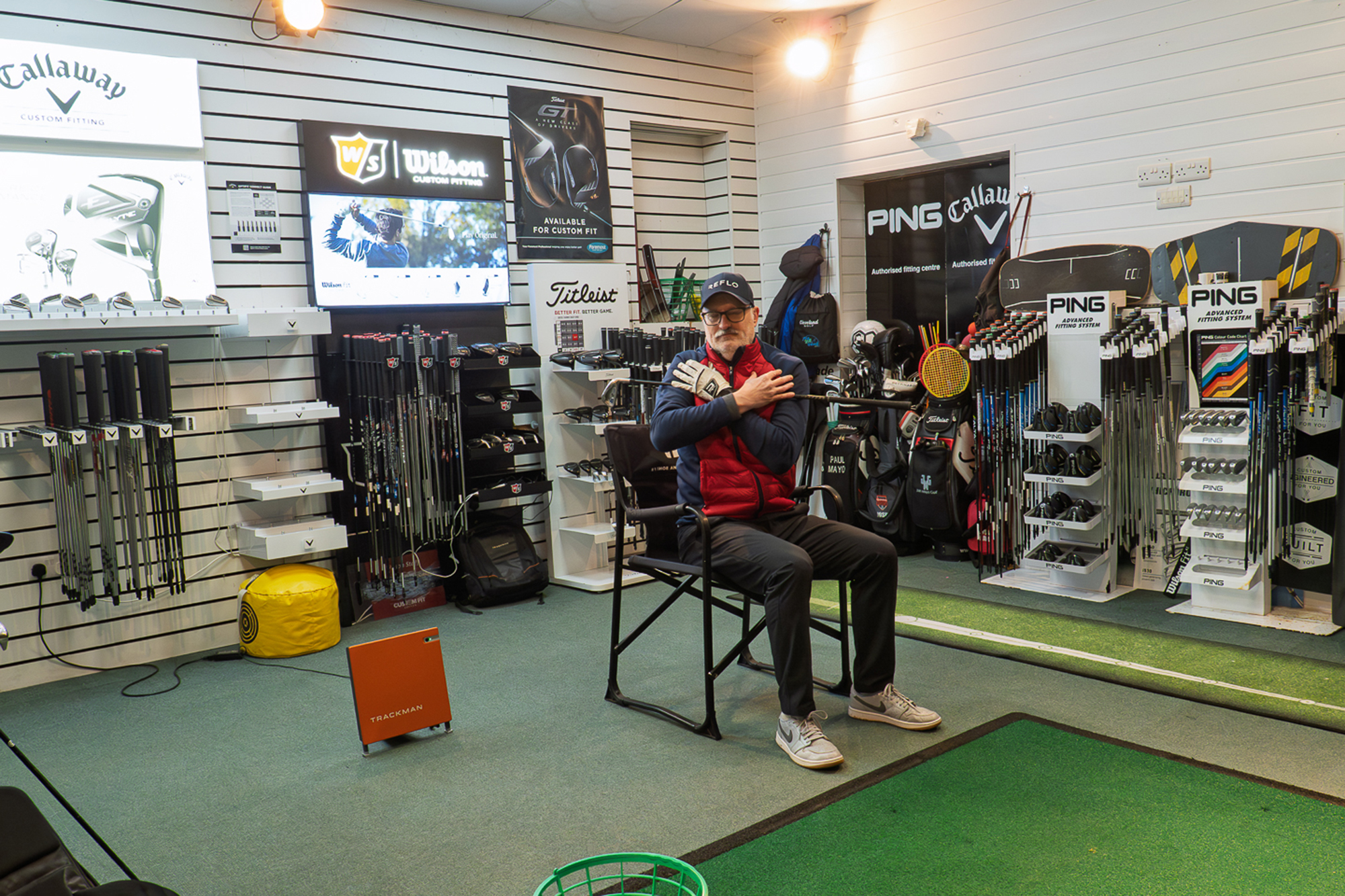 Rob Spedding doing a golf drill which requires him to sit on a chair and rotate with a golf swing across his chest