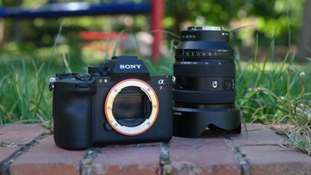 Sony A7R VI camera body beside a Sony FE 20-70mm G lens in grass.