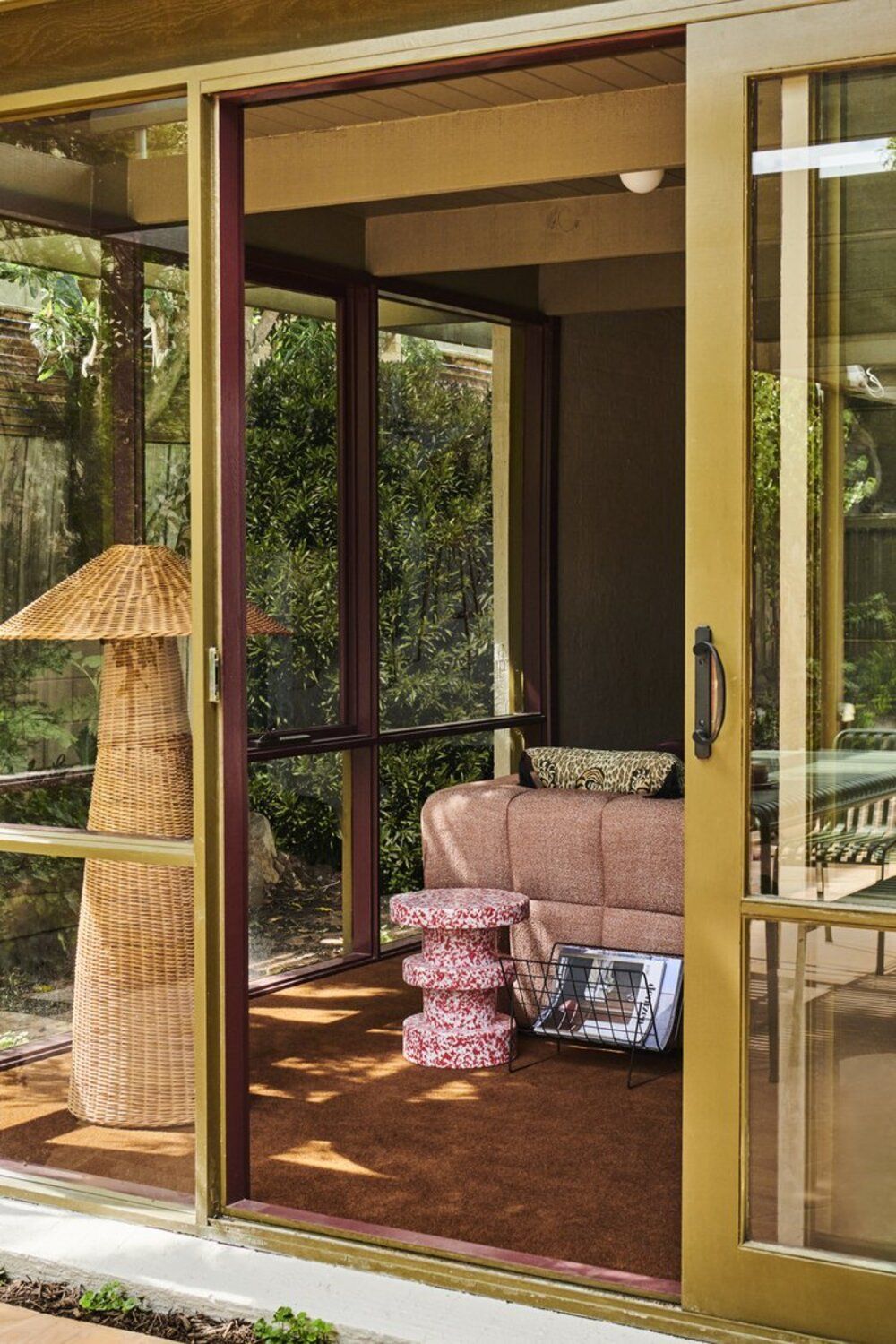 living room with orange carpet, rattan floor lamp, pink sofa, and yellow sliding doors