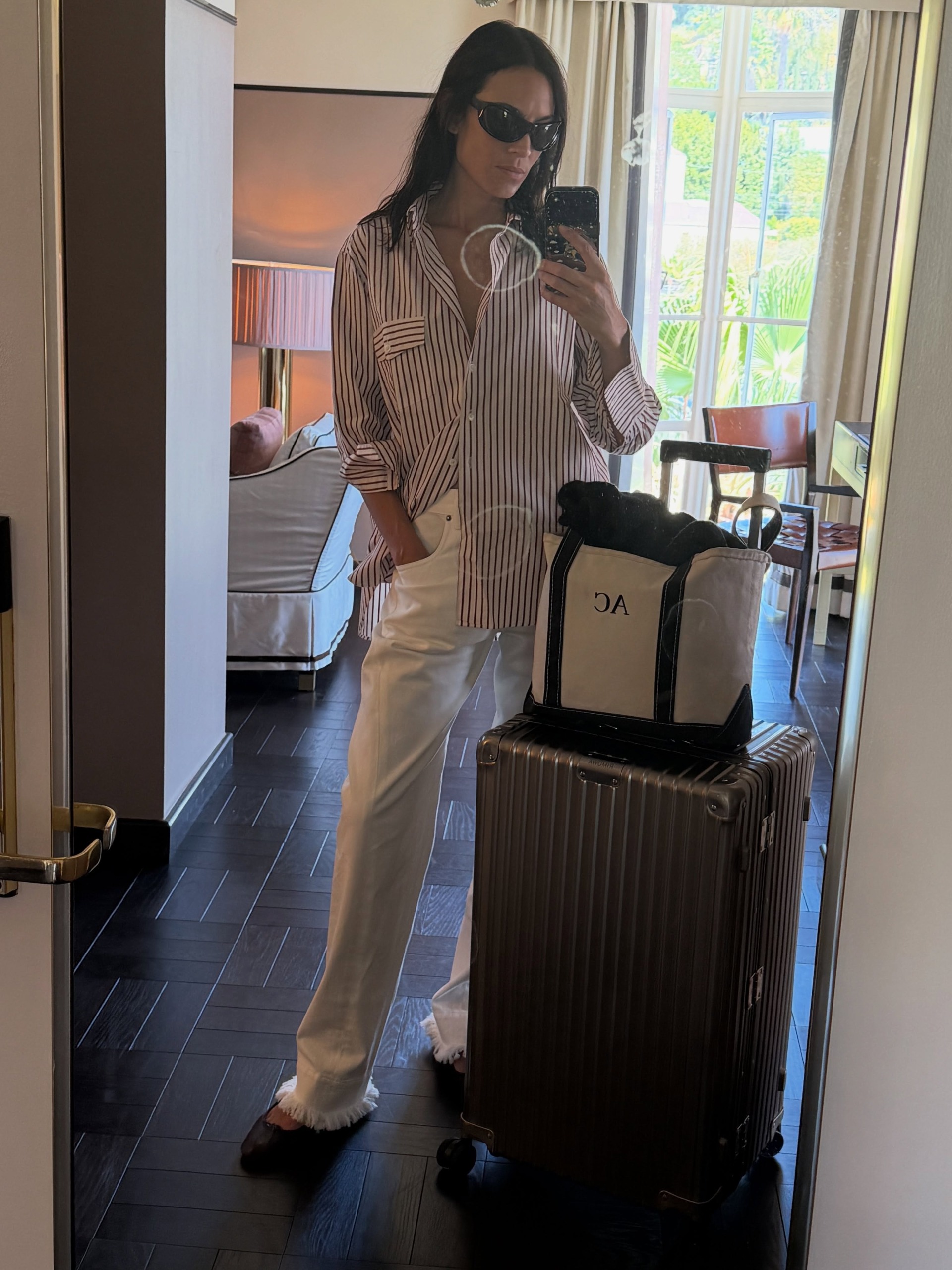 Alexa Chung takes a mirror selfie wearing white frayed jeans with an oversized shirt and t-shirt.