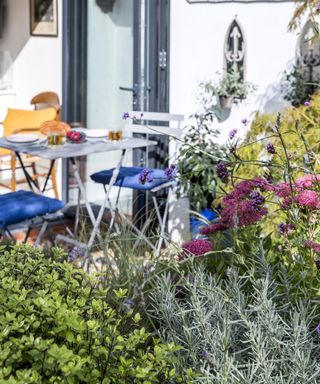 a garden bed in front of a bistro style seating area