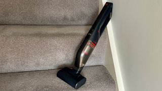 The Eufy HomeVac H30 Mate leaning up against a wall on a staircase