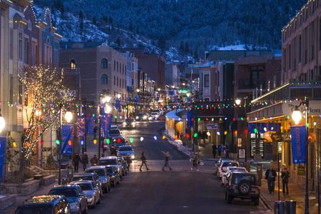 A family carrying skis walks across Main Street in Park City, Utah, at night