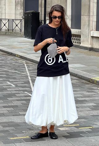 a photo of an influencer wearing a white ballon skirt with a long navy t-shirt and black ballet flats