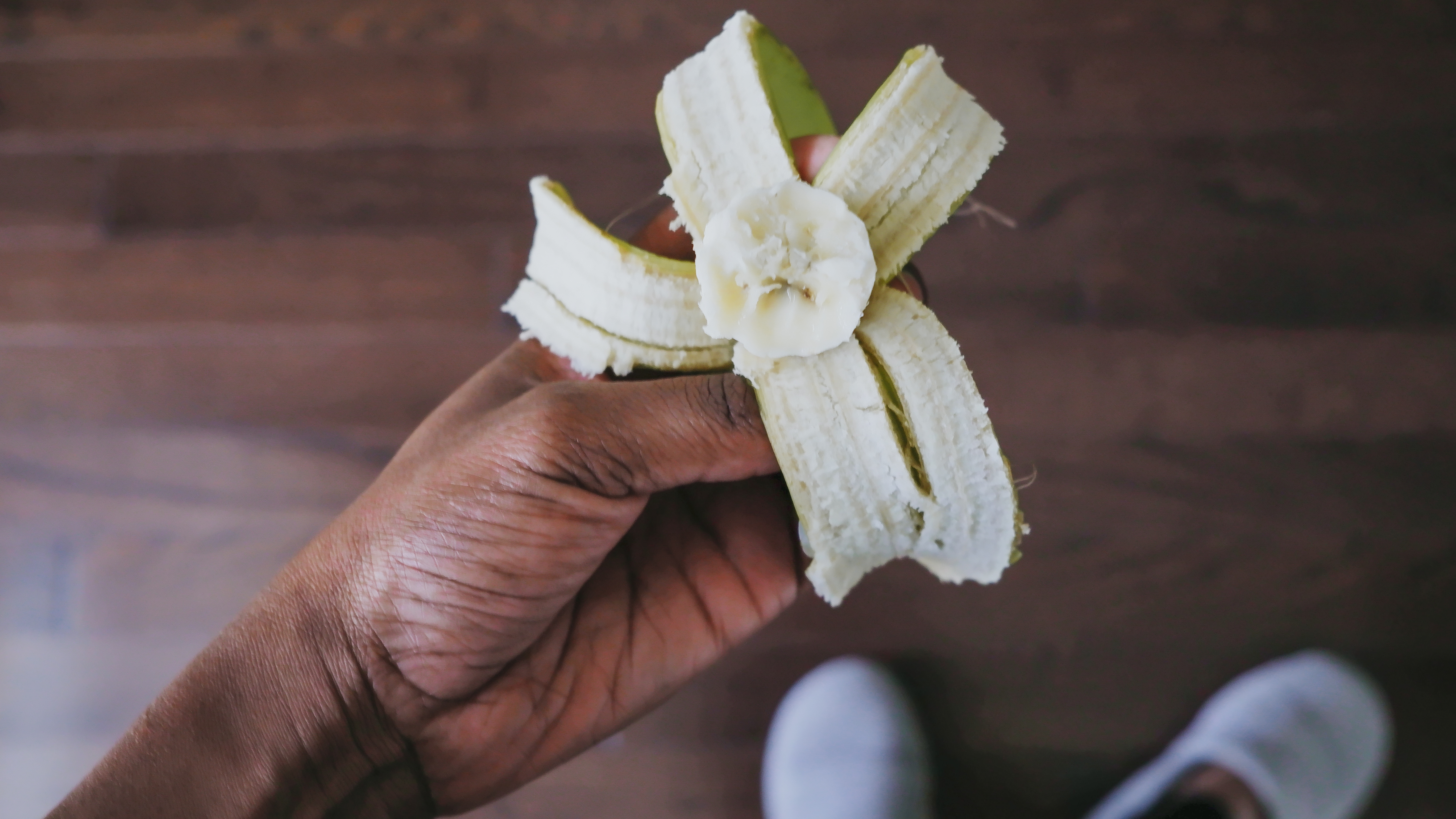 A person holds a half-eaten banana in their hands.