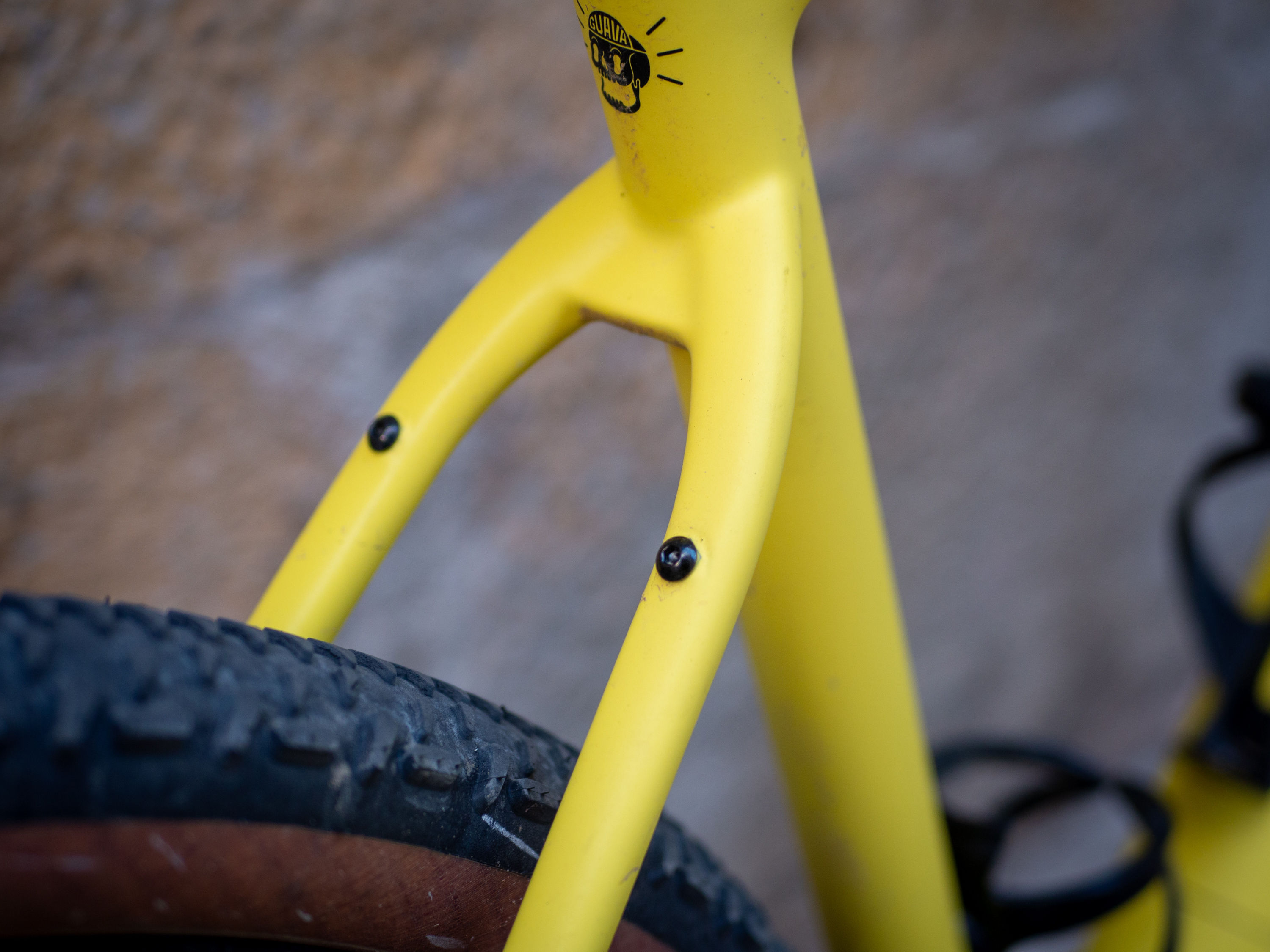 A yellow Guava Spot gravel bike leans against a wall