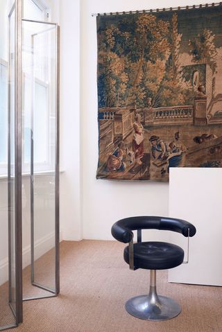 A glass screen that once belonged to Tom Ford and a Marzio Checchi chair stand in front of an antique Flemish tapestry