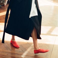 Model wearing The Row's mara jelly sandal flat in red walking on wood