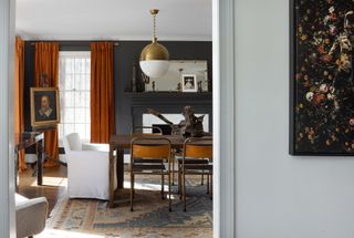 rug in gray dining room with orange curtains and bold pendant light above table